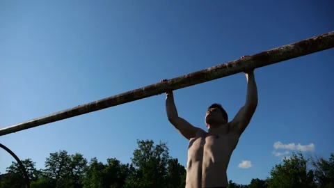 Athletic guy doing pull ups on football goal crossbar at stadium. Young muscular Stock Footage 344768350
