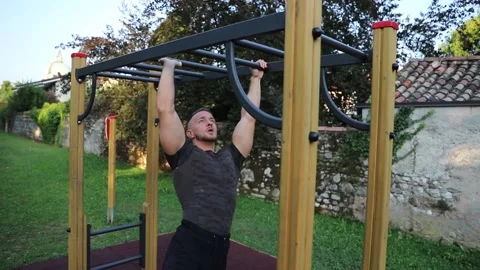 Athletic guy performs an exercise on parallel bars outdoor in a Park. Video stock 149747323