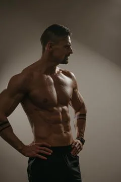 The athletic guy is posing. A bodybuilder is standing with his hands on his h Stock Photos