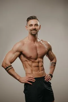 The athletic guy is posing. A bodybuilder is standing with his hands on his h Stock Photos