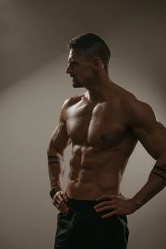 The athletic guy is posing. A bodybuilder is standing with his hands on his h Stock Photos