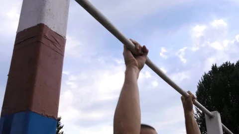 Athletic guy pulls himself up on a horizontal bar in a military camp for getting Stock Footage 116468217