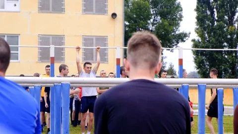 Athletic guy pulls himself on a horizontal bar in a military camp to get a Stock Footage 116468427