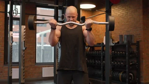 Athletic guy pumping his biceps with a barbell in the gym. Video stock 263801025