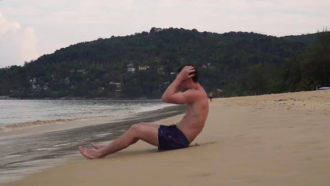 Athletic guy pumps press on the seashore Video stock 119802490