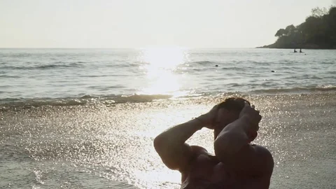 Athletic guy pumps press on the seashore Видео 123049511
