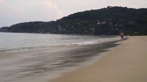 Athletic guy runs along the seashore Video stock 119802470