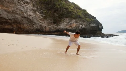 Athletic guy runs and does cool stunts on the Kelingking beach in Bali Stock Footage 126143039