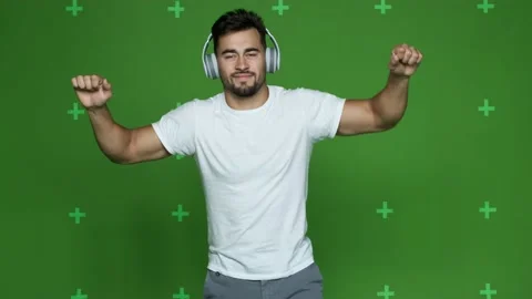 Athletic guy in white t-shirt listens to music in headphones and dances Stock Footage 130831404
