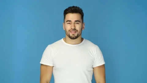 Athletic guy in white t-shirt smiling on blue background. Close up Stock Footage 130831553