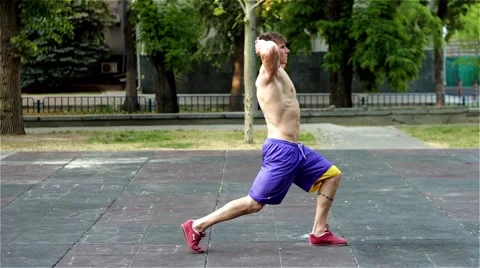 Athletic Guy working out at the street and swing the hamstrings by making squats Video stock 51374527