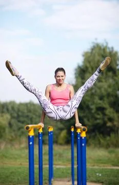 Athletic gymnast exercising on parallel bars Athletic attractive young fem... Stock Photos