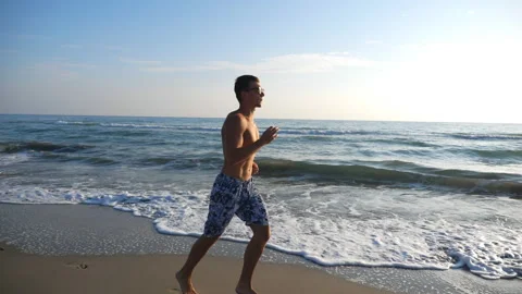 Athletic handsome guy jogging through coast with beautiful seascape Video stock 120777508