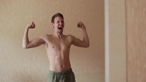 Athletic happy man posing in front of a mirror and smiling. A man looking at the Stock Footage 265017858