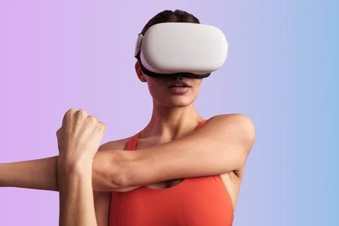Athletic lady stretching arms while experiencing virtual reality in headset Stock Photos