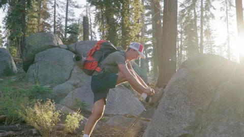 Athletic male backpacker lit by sunrays ties shoelaces on hiking boots, Yosemite Stock Footage 270496635