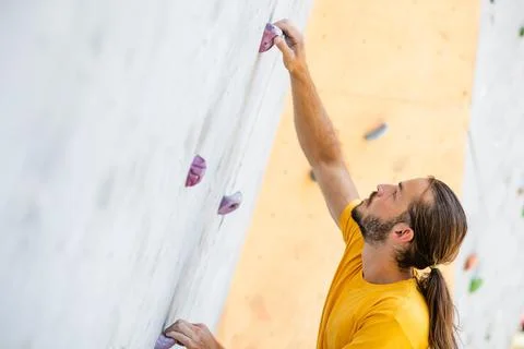 Athletic male climbing on a climbing wall. Stock Photos