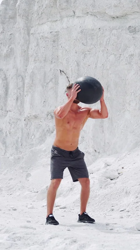 An athletic male strongman does exercises with a fitness ball to strengthen Video stock 274055756