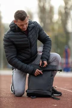 Athletic man with backpack posing on sports ground outdoors Stock Photos