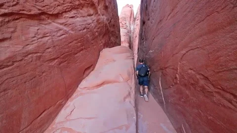 An athletic man with backpack walks through chasm in Arches National Park Stock Footage 155034976