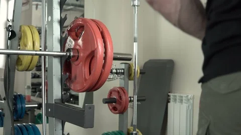 Athletic man with a beard hangs a disc on the bar close-up 4k. Stock Footage 85588516