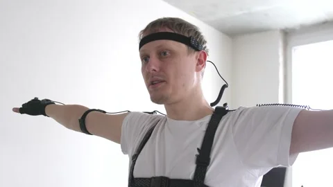 Athletic man with beard wears motion capture suit with sensors headset moving in Stock Footage 153426298