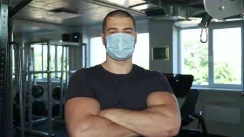 Athletic man with big biceps standing in the gym in a mask in a male with his Stock Footage 134576454