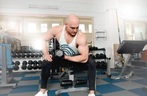 Athletic man bodybuilder do execute exercise with dumbbells Stock Photos