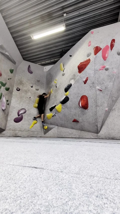 Athletic man bouldering on indoor climbing wall in modern fitness gym Video stock 335638121