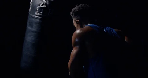 An athletic man in boxing gloves hits a punching bag Stock Footage 83380830