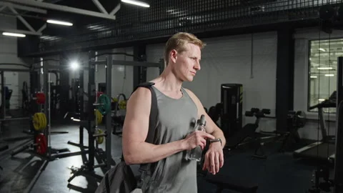 Athletic Man Checking Smartwatch with Water Bottle in Gym Stock Footage 339890099
