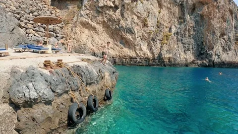 Athletic Man Cliff Jumping into the Sea. Slow Motion. Young Man Jumps off Cliff  Video stock 169908144