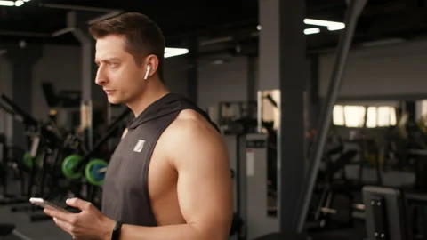 Athletic man does cardio training on treadmill in gym and looks at smartphone Stock Footage 172393454