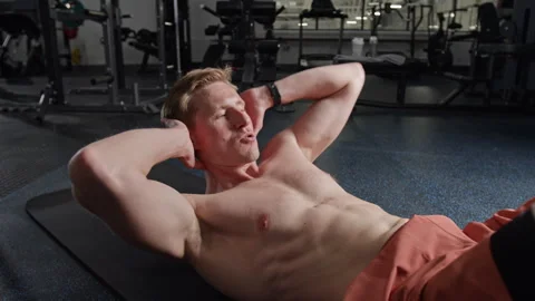 Athletic Man Doing Abdominal Crunches on Mat in Fitness Center Stock Footage 339909924