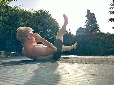 Athletic man doing abs exercise in his garden in the morning Stock Photos