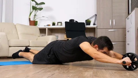 Athletic man doing abs exercises with an ab wheel Stock Footage 95635572