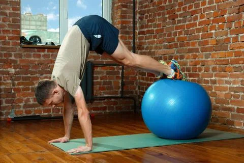 Athletic man doing balancing exercises with the gym ball Stock Photos