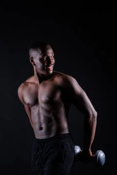 Athletic man doing exercise for arms with dumbbells. Muscular fitness model Stock Photos