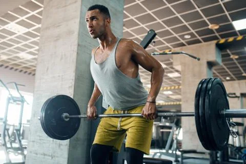Athletic man doing exercise with barbell in gym Stock Photos