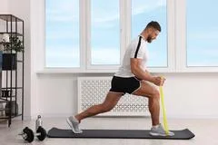 Elder adult sitting on yoga mat and pulling resistance band Stock Photo by  DC_Studio