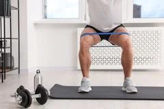 Elder adult sitting on yoga mat and pulling resistance band Stock Photo by  DC_Studio