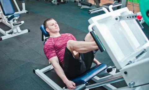 Athletic man doing exercise press leg machine in gym. Power training Stockfoto's