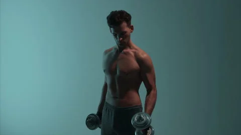 The athletic man is doing exercises with dumbbells Stock Footage 148775746