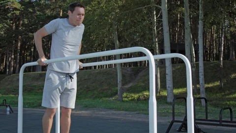Athletic man doing gymnastic exercise on parallel bars wearing smartwatches. Stock Footage 94916492