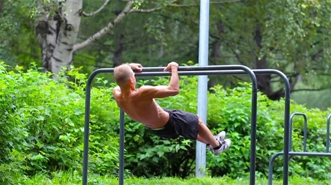 Athletic man doing gymnastics elements on bars in City Park 動画素材 66420648