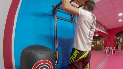 Athletic Man Doing Hanging Leg Raises and Pull Ups Exercise on Wall Mounted Bar Stock Footage 323868533