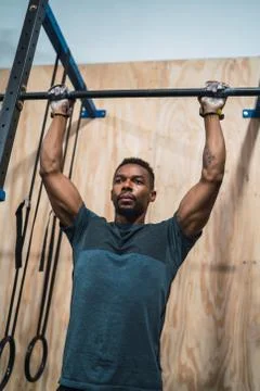 Athletic man doing pull up exercise at the gym. Stock Photos