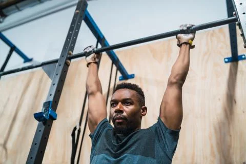 Athletic man doing pull up exercise at the gym. Stock Photos