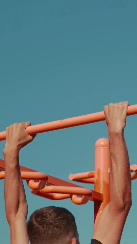Athletic man doing pull-ups on horizontal bar outdoors, close up. Vertical video Video stock 308529880
