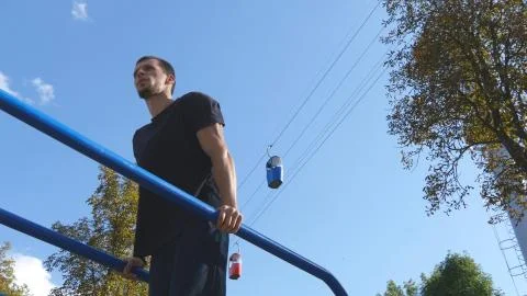 Athletic man doing push ups on parallel bars at sports ground in city park 스톡 사진